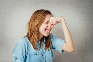 Kadın jesti kötü kokar, kapalı burun. Gri arkaplanda izole