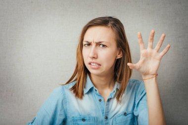 Kötü davranışları olan, el hareketleriyle el hareketi yapan, beyaz arka planda izole edilmiş genç, rahatsız bir kadının yakın plan portresi. Negatif insani duygu, yüz ifadesi hissi, vücut dili