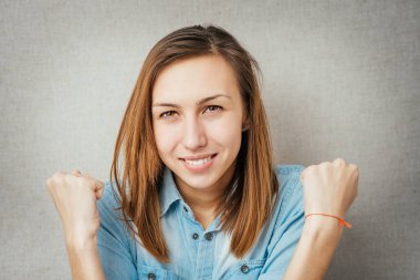 Gri arka planda zafer işareti yapan genç bir kadının portresi