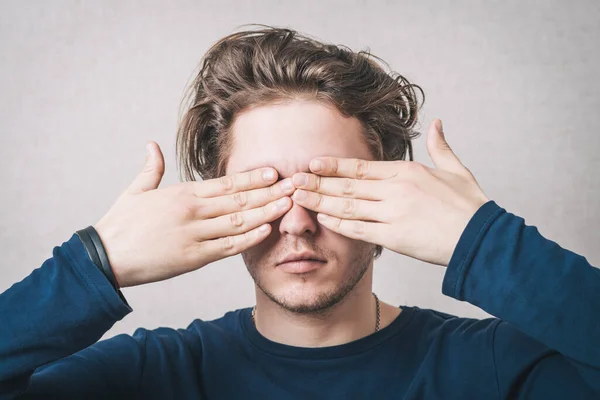 Man Sloot Zijn Ogen Met Zijn Handen Een Grijze Achtergrond — Stockfoto