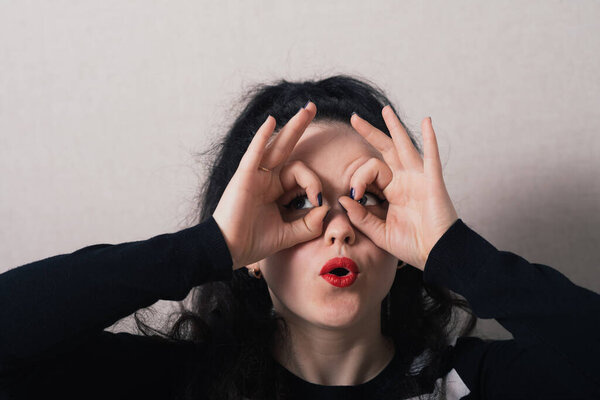 A woman with long hair with hand over eyes, looking through fingers