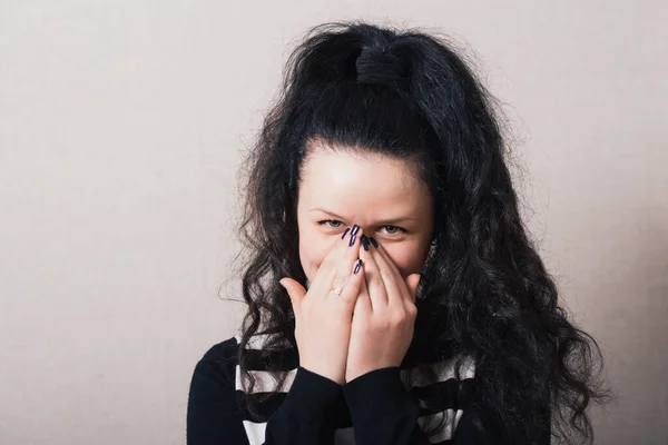 Woman laughing covering his face. Gray background