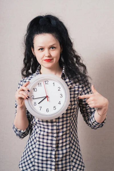 Γυναίκα Δείχνει Ένα Ρολόι Τοίχου Γκρι Φόντο — Φωτογραφία Αρχείου