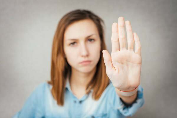Closeup portrait of young annoyed woman with bad attitude, giving talk to hand gesture with palm outward, isolated on white background. Negative human emotion, facial expression feeling, body language