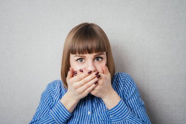 Güzel genç bir kadın eliyle yüzünü kapatıyor.