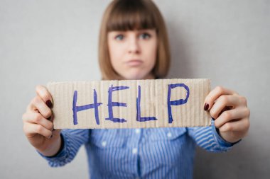 Stresli iş kadını yardım için yalvarıyor, elinde bir karton ile yardım