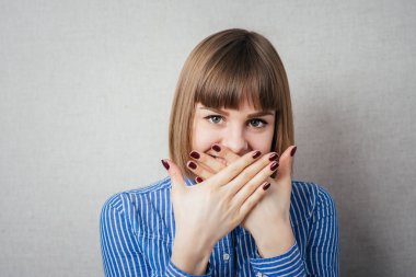 Güzel genç bir kadın eliyle yüzünü kapatıyor.