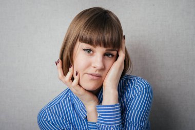 Genç, üzgün, üzgün, depresif, endişeli, iki eliyle başını tutmakta olan esmer kadının yakın plan portresi. İnsani duygular, yüz ifadeleri, duygular, algı