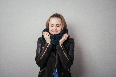 Hava çok soğuk. Donmuş genç kadınlar, gri arka planda dikilirken balıkçı yaka kazakla yüzlerini örtüyorlar.