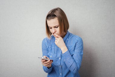 Kız cep telefonuna bakıyor ve düşünüyor.