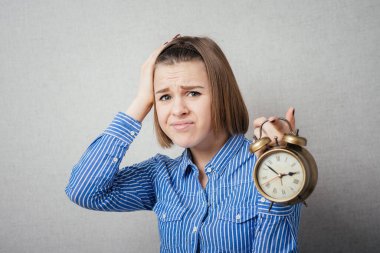 Kız içeri giriyor ve elinde bir çalar saat tutuyor.