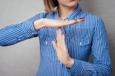 Ciddi kız jestleri mola veriyor, gri renkte izole edilmiş.