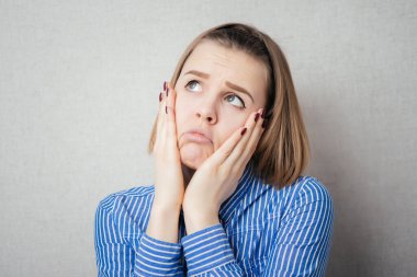 Sinüs basıncı ağrısı olan genç bir kadın, gri arka planda izole edilmiş.