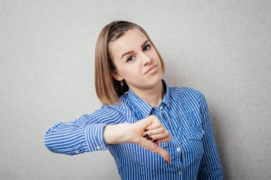 Gri arka planda izole edilmiş güzel genç kız olumsuz hayal kırıklığı kavramı