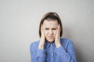 Genç kadın kulaklarını kapatıyor.