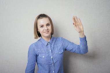 Genç kadın el sallıyor, gülümsüyor.