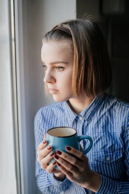 Sabahları kahve içen kadın pencerenin kenarında oturuyor..