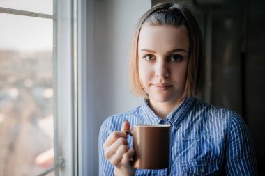Sabahları kahve içen kadın pencerenin kenarında oturuyor..