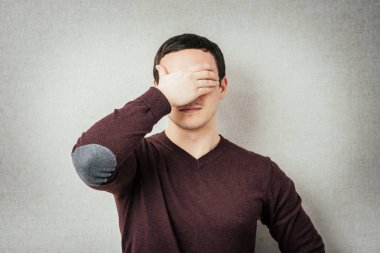 Adam elleriyle yüzünü örttü.