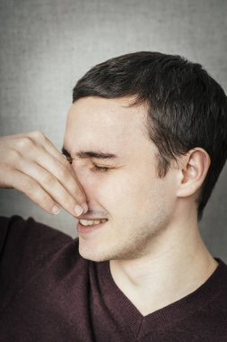 Burnunu kapatan yakışıklı bir adamın portresi. Çünkü bir şey kokuyor.