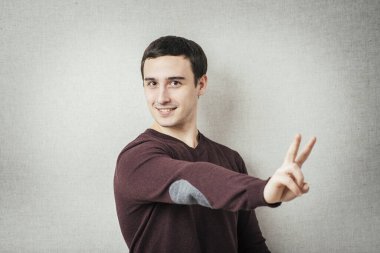 Zafer ya da barış işareti gösteren genç adam