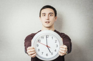 Gri Arkaplanda Saat Tutan Genç Bir Adamın Portresi