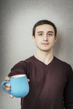 Genç adam bir fincan çay ikram ediyor.