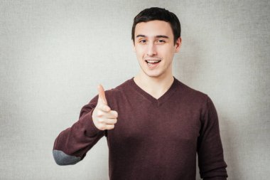 Gri arka planda izole edilmiş kameraya bakan yakışıklı genç adam.