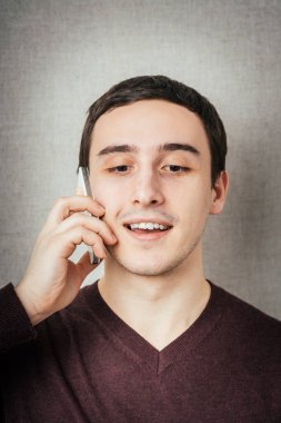 Mutlu gülümseyen genç adam cep telefonundan konuşuyor. 