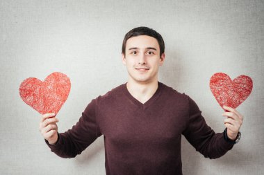 Elinde kırmızı bir kalp tutan genç bir adam.