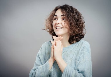 Gri arka planda şaşırmış genç bir kadının yakın çekimi