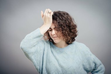 Gri arka planda izole edilmiş güzel, üzgün, sıradan bir kadın.