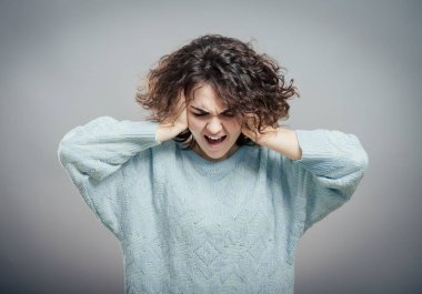 Genç, üzgün, üzgün, depresif, endişeli, iki eliyle başını tutmakta olan esmer kadının yakın plan portresi. İnsani duygular, yüz ifadeleri, duygular, algı