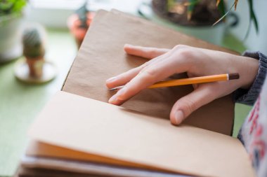 Kağıda kalem yazan insan elleri.