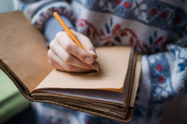 Kağıda kalem yazan insan elleri.