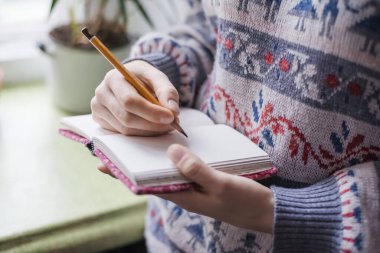 Kağıda kalem yazan insan elleri.