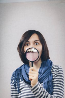 Genç kız büyüteçle ağzını gösteriyor.