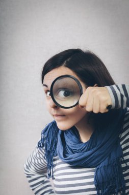 Genç kız büyüteçten bakıyor.