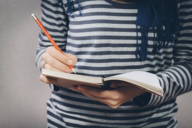 Genç bayan deftere bir şeyler yazıyor.