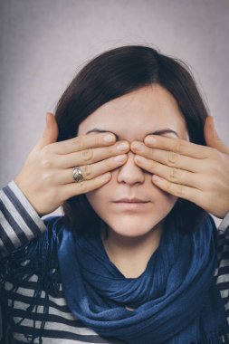Genç bir kadın elleriyle gözlerini kapatıyor.