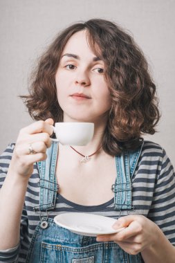 Kahve içen, tulum giymiş bir kız.