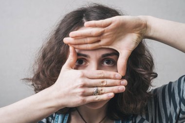 Gözlere çerçeve yapan, tulum giymiş bir kız.