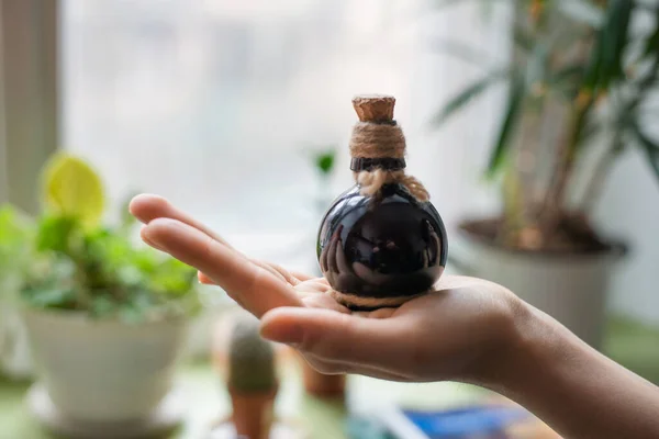 hands holding a small black bottle with stopper