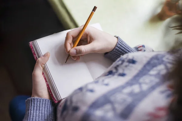 Human hands with pencil writing on paper