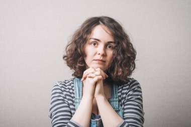 Kadın dua ederken ellerini kavuşturdu. Gri arkaplan