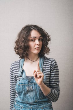 Kadın işaret parmağını gösteriyor, nazikçe dikkat et. Gri arkaplan