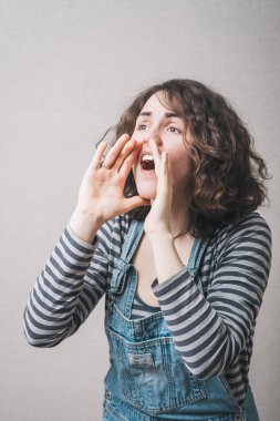 Elleri ağzında olan birini çağıran bir kadın jest yapar. Gri arkaplan