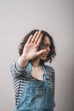 Bir kadın jest molası veriyor. Gri bir arkaplanda.