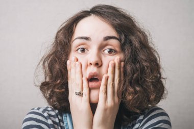 Kadın düşündü, üzüldü, düşündü, duygular, korku. Gri bir arkaplanda.