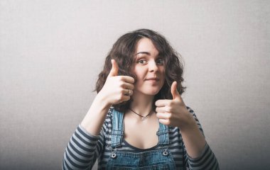 İki parmağını kaldıran bir kadın. Gri bir arkaplanda.